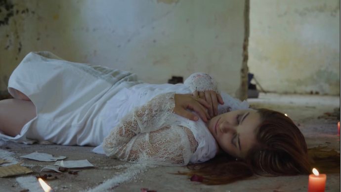 Still de El último deseo: la protagonista acostada en el piso junto a una vela