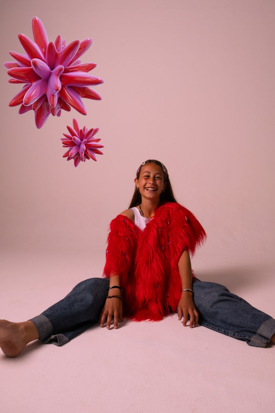 Chica sentada en el piso con tapado rojo de pelo y flores 3D