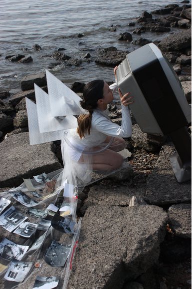 Modelo con accesorios plisados de plástico translúcido junto a un televisor
