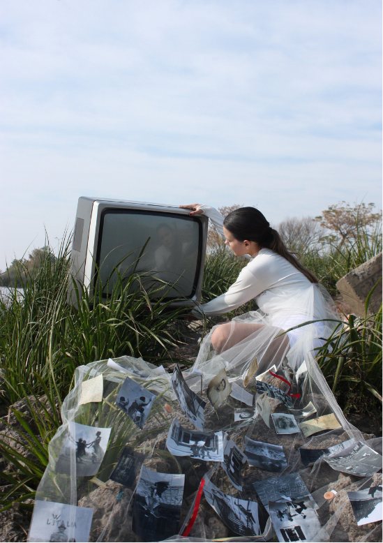 Modelo agachada junto a un televisor antiguo entre los pastos