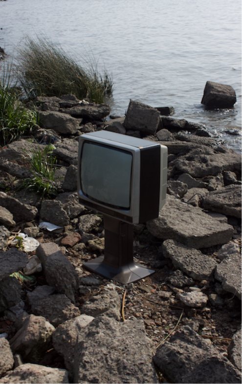 Televisor antiguo apoyado sobre las rocas frente al río